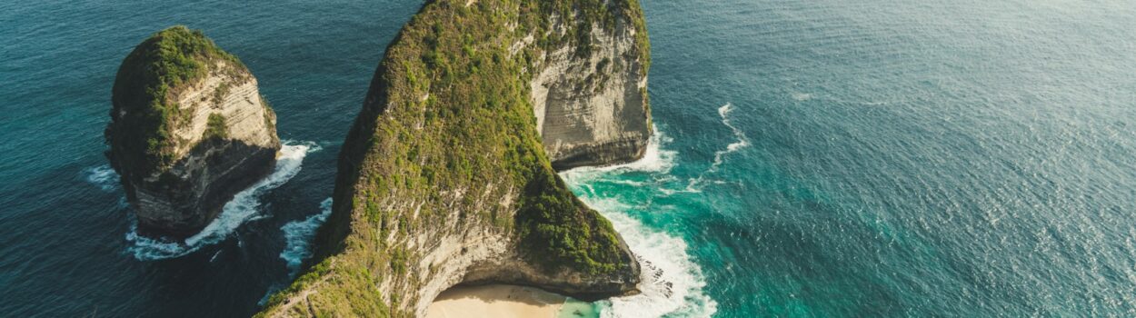aerial photo of green dense island in teal calm body of water at daytime