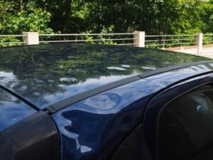Voiture noire sur un pont au-dessus d'une rivière, entourée d'arbres