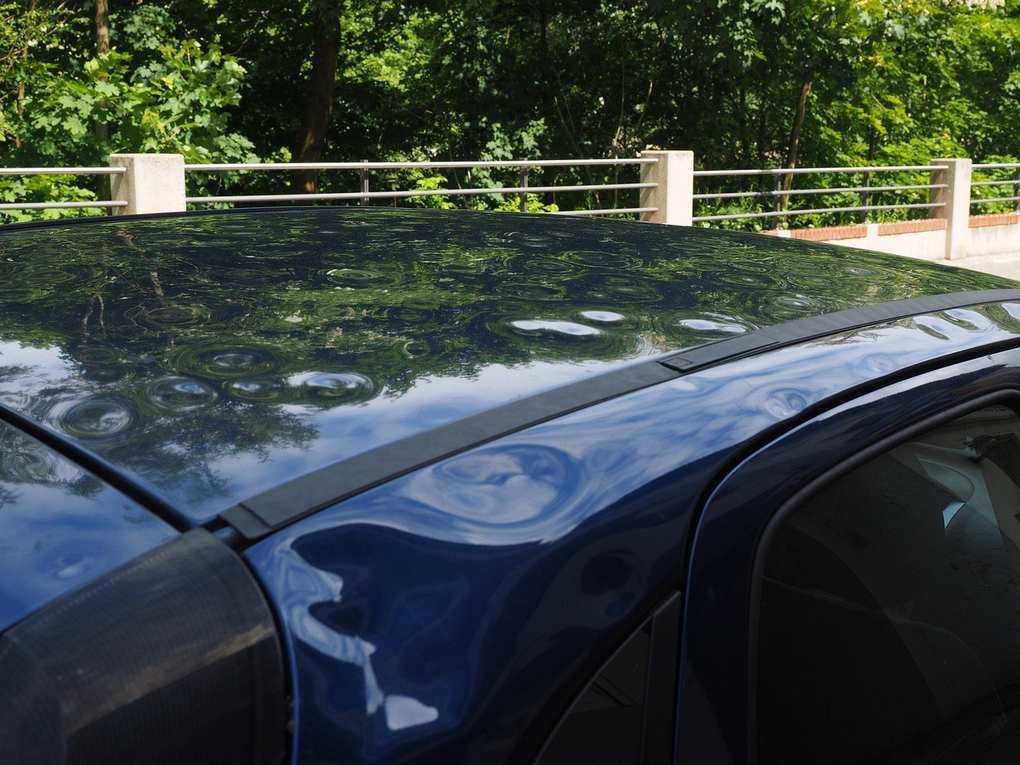 Voiture noire sur un pont au-dessus d'une rivière, entourée d'arbres Voiture noire sur un pont au-dessus d'une rivière, entourée d'arbres