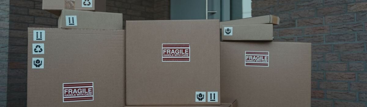 Piles de cartons FRAGILE empilés devant une porte d'un bâtiment en brique