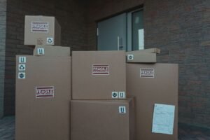 Piles de cartons FRAGILE empilés devant une porte d'un bâtiment en brique