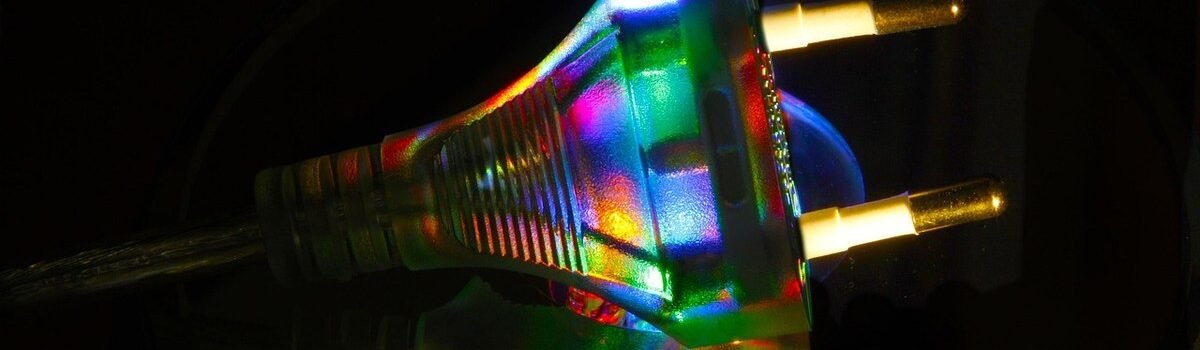 Une prise électrique illuminée par des reflets multicolores sur un fond noir