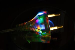Une prise électrique illuminée par des reflets multicolores sur un fond noir