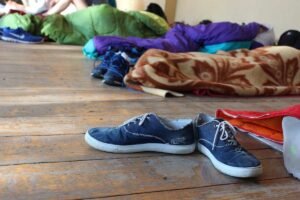 Chaussures, vêtements et équipements de camping dispersés sur sol en bois