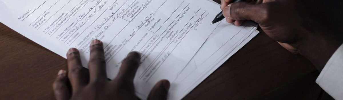 Mains noires écrivant sur un papier avec un stylo sur une table