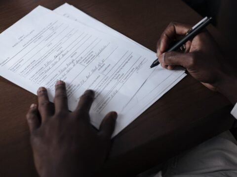 Mains noires écrivant sur un papier avec un stylo sur une table
