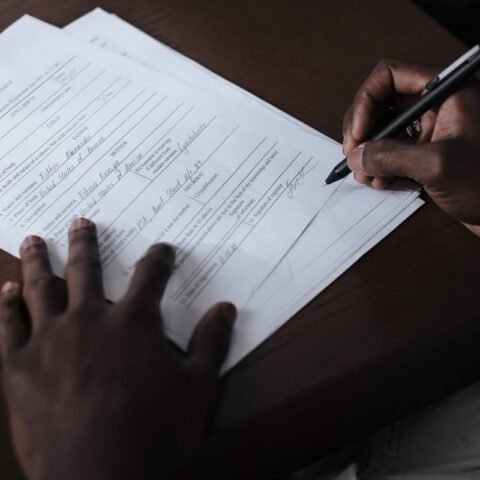 Mains noires écrivant sur un papier avec un stylo sur une table