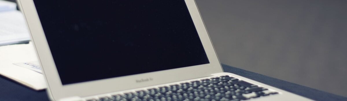 Ordinateur portable blanc avec écran noir posé sur une surface de travail grise