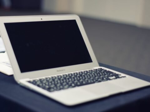 Ordinateur portable blanc avec écran noir posé sur une surface de travail grise