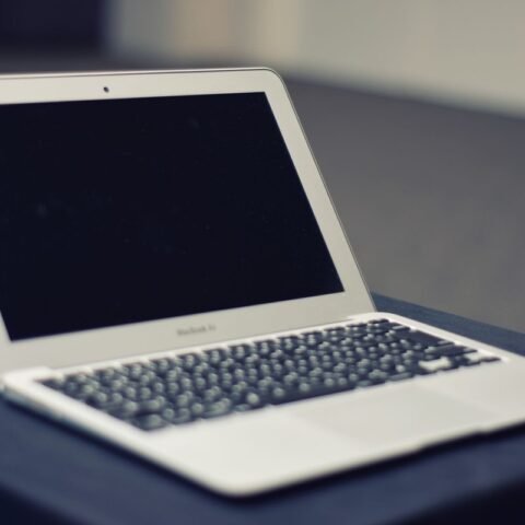 Ordinateur portable blanc avec écran noir posé sur une surface de travail grise