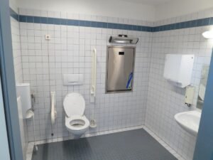 Bloc sanitaire de camping avec toilettes, lavabo, miroir et distributeurs de savon et papier