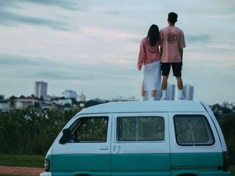 Un couple se tient debout sur le toit d'un van turquoise