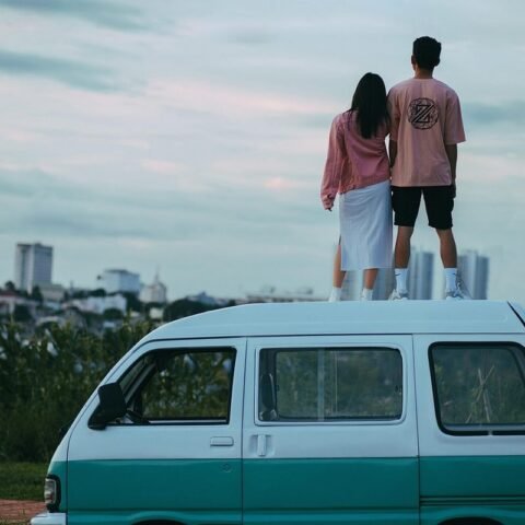 Un couple se tient debout sur le toit d'un van turquoise