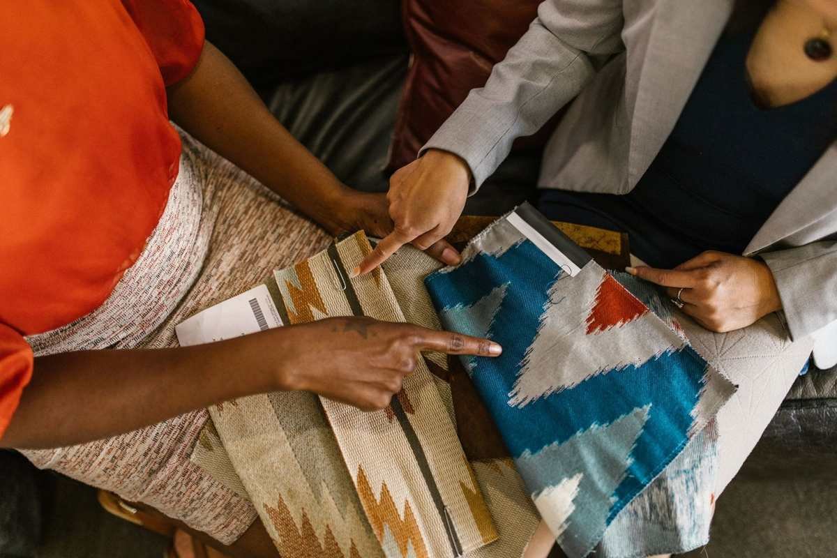 Deux mains indiquent des tissus colorés sur une table