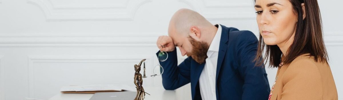 Homme et femme en réunion professionnelle, documents et statue de justice sur le bureau