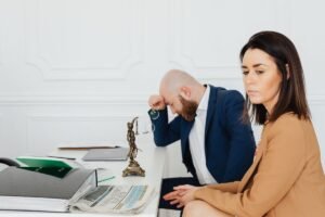 Homme et femme en réunion professionnelle, documents et statue de justice sur le bureau