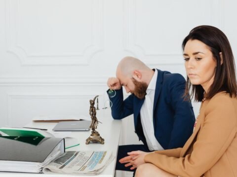 Homme et femme en réunion professionnelle, documents et statue de justice sur le bureau