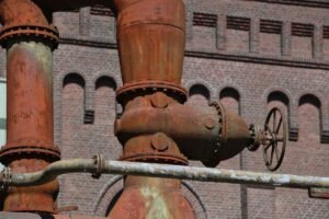Pipes rouillés et vanne à main devant un mur de brique