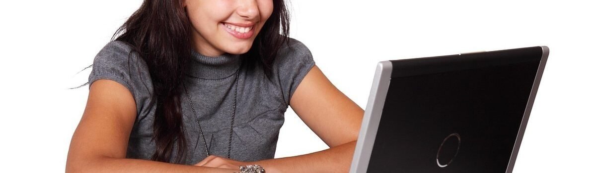 Femme souriante utilisant un ordinateur portable, visage tourné vers l'écran