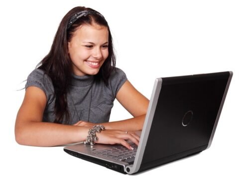 Femme souriante utilisant un ordinateur portable, visage tourné vers l'écran