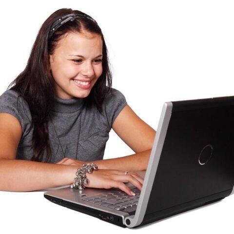 Femme souriante utilisant un ordinateur portable, visage tourné vers l'écran