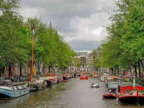 Vue d'un canal bordé d'arbres, de bateaux et de bâtiments anciens