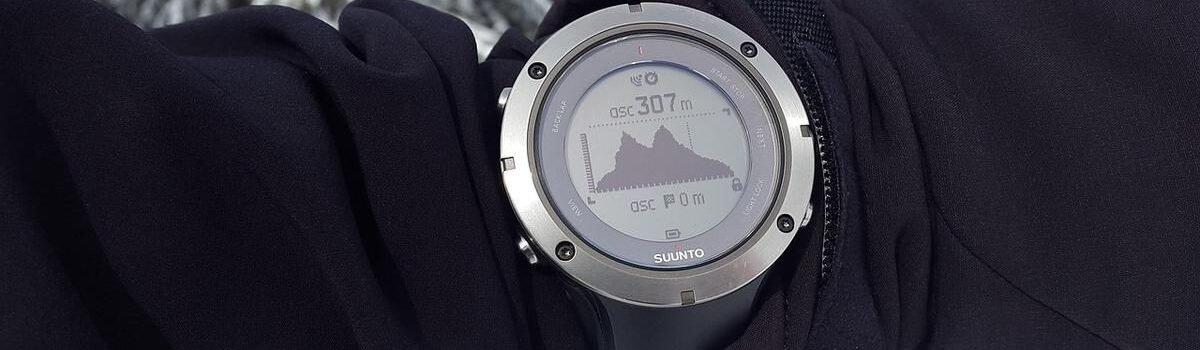 Montre connectée montrant une montagne sur son écran, portée sur un bras ganté