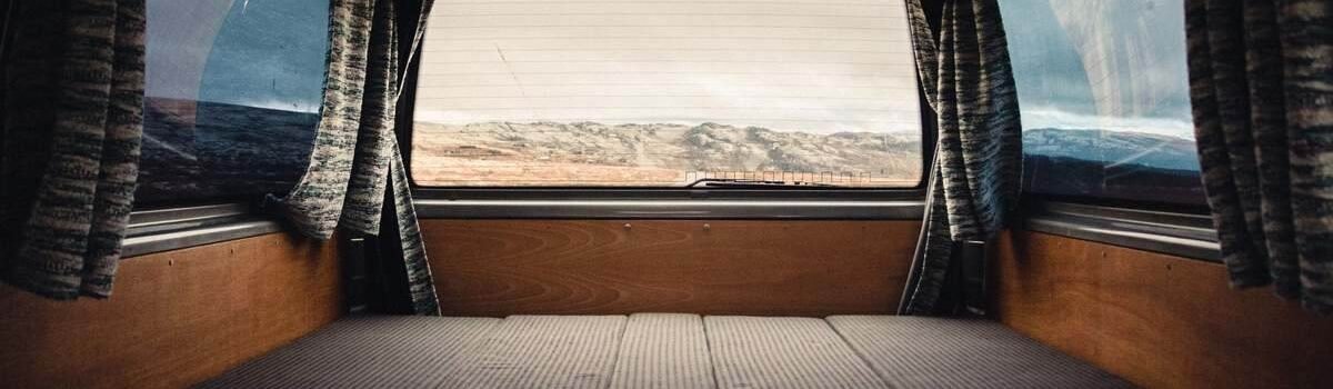 Intérieur d'un véhicule camper avec lit pliant, rideaux et vue extérieure