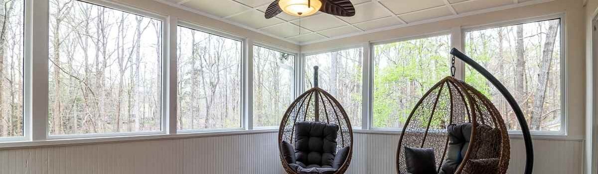 Deux fauteuils suspendus, ventilateur, grandes fenêtres, plancher en bois