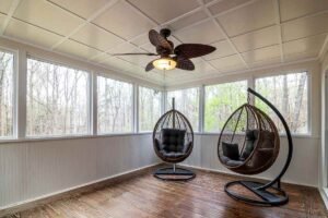 Deux fauteuils suspendus, ventilateur, grandes fenêtres, plancher en bois
