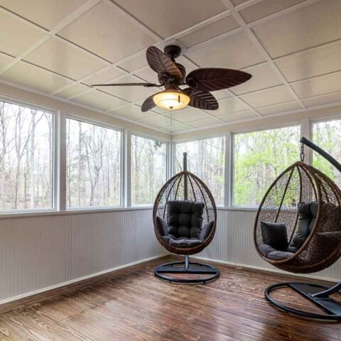 Deux fauteuils suspendus, ventilateur, grandes fenêtres, plancher en bois