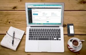 Un ordinateur portable ouvert sur une table en bois avec accessoires