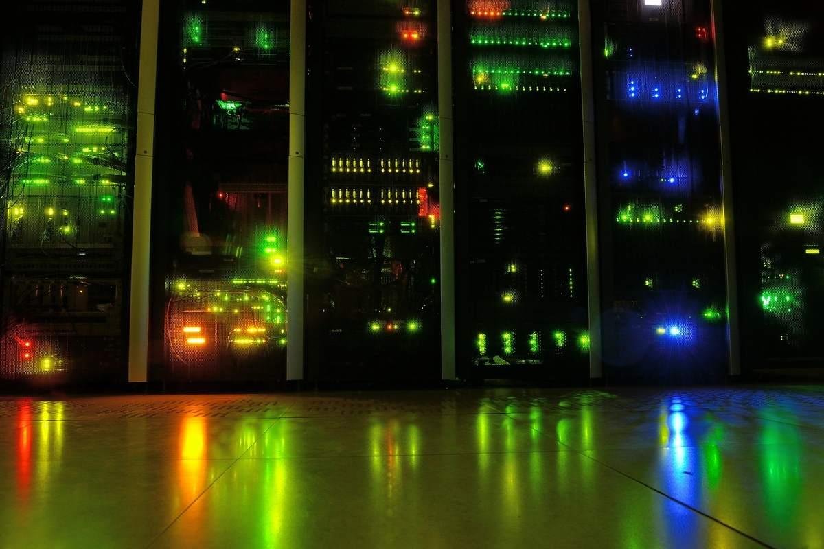 Baies de serveurs avec voyants verts, rouges et bleus allumés dans une salle sombre