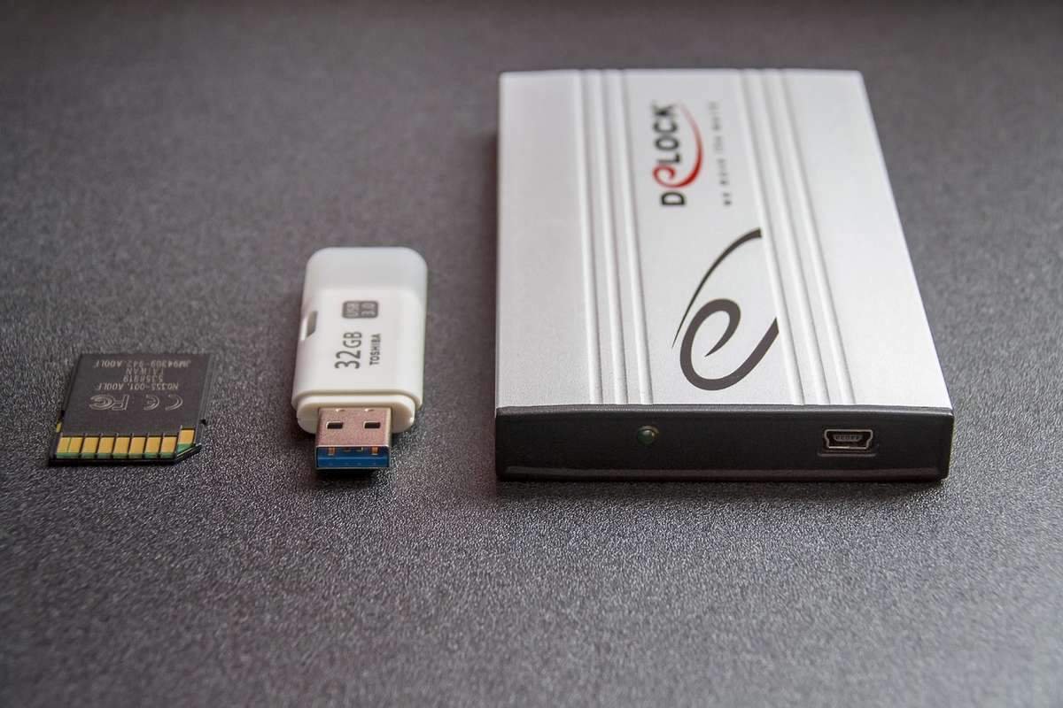 Carte SD, clé USB, et boîtier externe sur fond gris